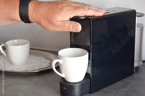 Konstfotografi A close-up of a man pressing a button on a modern capsule coffee machine to prepare a fresh morning cup of coffee