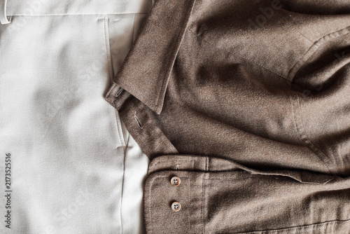 Flat lay of brown button-down shirt paired with light beige trousers showcasing textile textures.