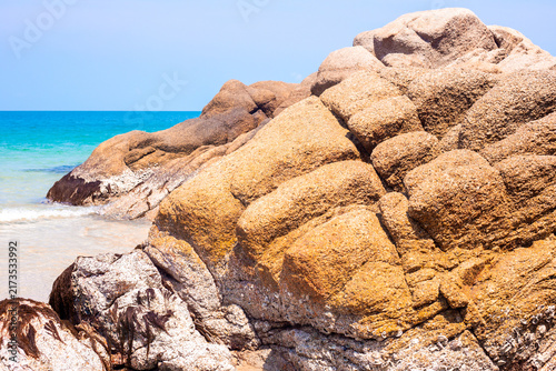 A close up shot of a giant texture rock on a sandy tropical coast. Koh Phangan island travel atmosphere, calm Thailand holiday beach artwork layout.