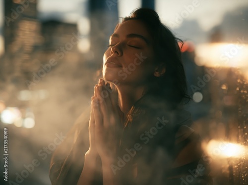 Woman praying with closed eyes at golden hour