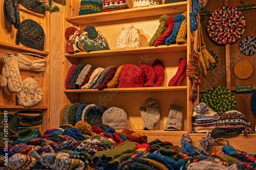 Cuadro en lienzo Colorful handmade winter hats, knitted mittens, and gloves neatly stored on wooden market stall shelves