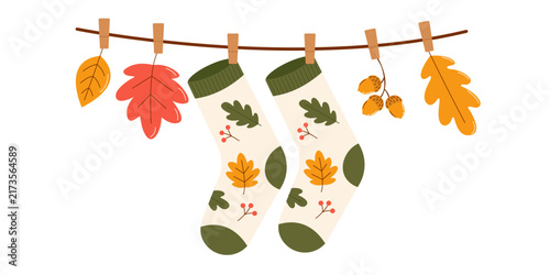 Warm socks, autumn leaves, and acorns hang on a clothesline with clothespins, creating an autumnal atmosphere and coziness. A natural garland