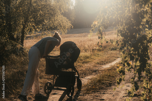 Foto Mother Looking into Baby Stroller during Golden Hour Walk in Park