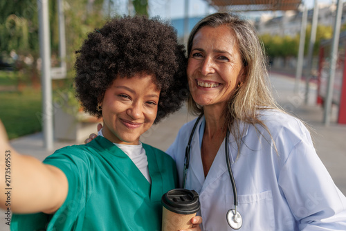 Two happy female doctors taking a selfie celebrating teamwork and diversity in healthcare