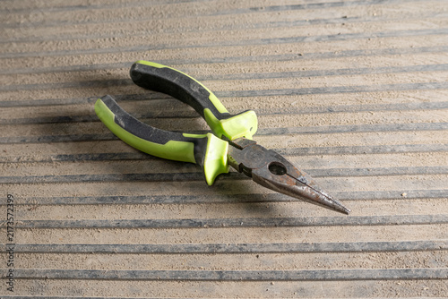 Obraz na plátne Pliers resting, in corrugated metal surface, with pliers, from a top-down perspective, with green, black accents, and industrial mood, with nearby objects, in surrounding setting