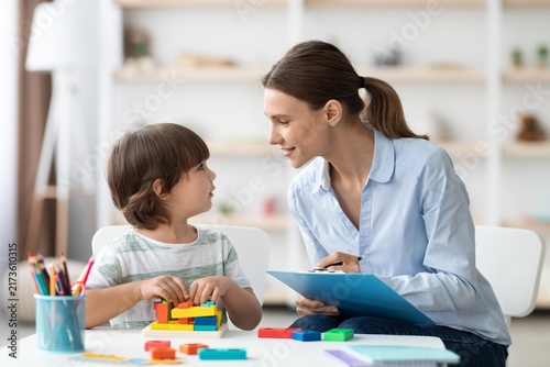 Fotografía Focused Caucasian Mother Engaging In Educational Activity With Young Boy At Home, Smiling While Interacting With Child Creating Colorful Blocks On Table