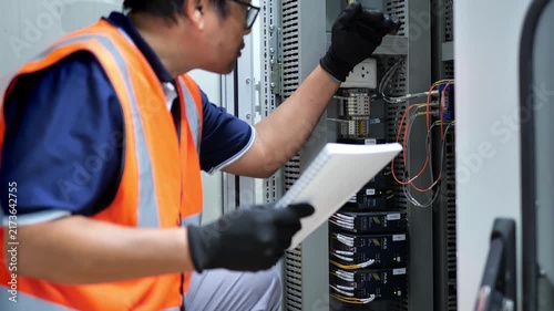 Experienced engineer examining fiber optic communication equipment and electronic modules in a network cabinet, representing digital data transmission, telecommunications infrastructure, network maint