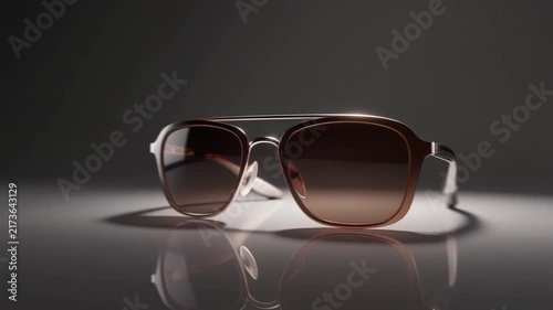 Modern aviator sunglasses with gradient lenses resting on a reflective surface within motion video clip animation