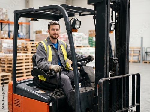 Male employee operating industrial forklift in modern warehouse
