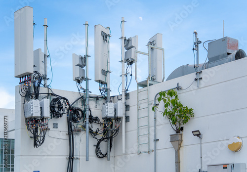 Quadro su tela Telecommunications cellular network antenna tower equipment with cables installed on the concrete roof of a commercial building