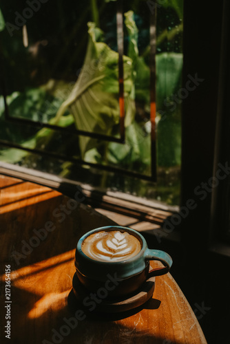 Aesthetic cafe scene with an artisanal cup of coffee, rich moody tones, and striking shadows from the morning sun