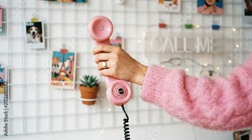 Person Holding Pink Vintage Telephone with Wall Grid Background.
