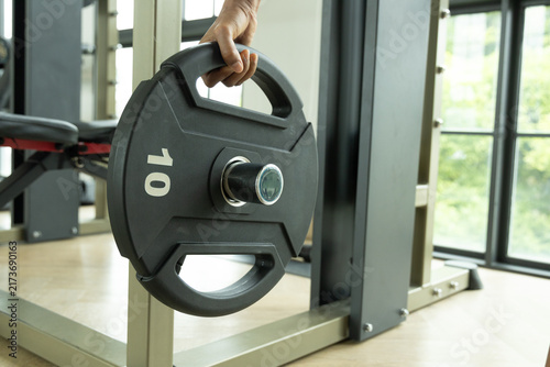 Konstfotografi Close-up image of sportsman putting heavy weight plates on barbell before exerci