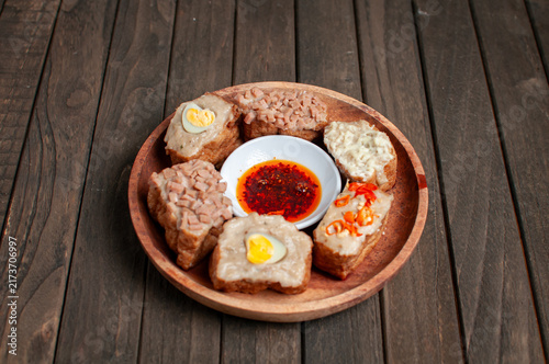 Foto a wooden plate of tahu bakso (tofu stuffed with meat paste) served with various toppings and a dipping sauce