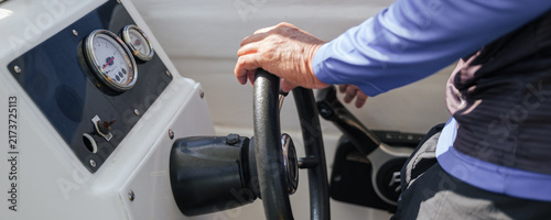Принти на полотні Person holding steering wheel while navigating boat on water, operating maritime