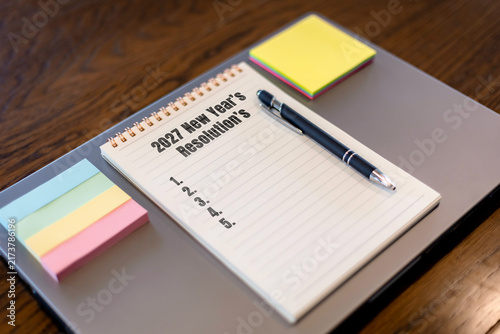 Bild auf Leinwand Notebook with 2027 New Year's Resolutions list, pen and sticky notes on desk, go