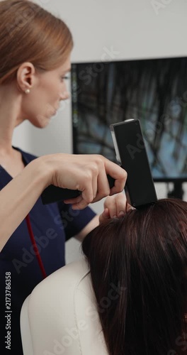 Professional trichologist clinician using diagnostic scalp scanner to evaluate hair and follicles for trichology treatment.