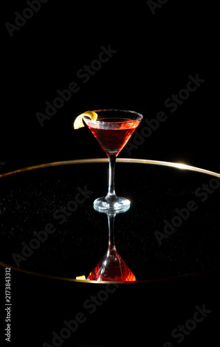 Elegant martini glass with red cocktail on black background.