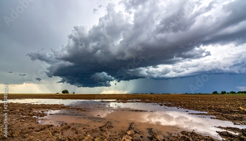 Dramatic Storm Clouds Over Muddy Agricultural Field with Rainwater Reflections