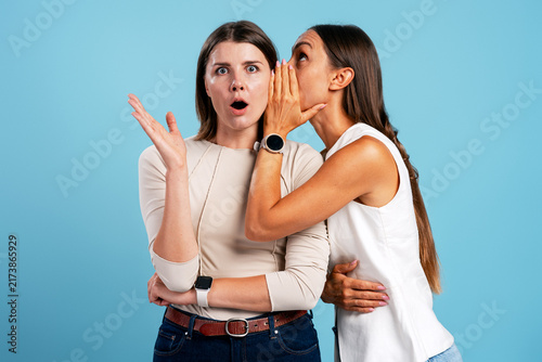 Konstfotografi Woman whispering secret gossip causing friend's surprise