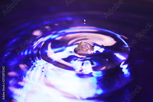 Water Drops Falling on Purple Blue Liquid Surface with Concentric Wave Ripples Close Up