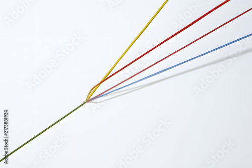 Vibrant colored elastic bands crisscrossing on a stark white surface, forming a central knot. A simple, modern, geometric composition.