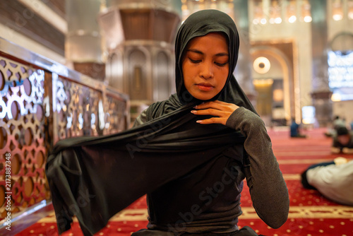 Canvastavla Muslim woman adjusting hijab, preparing for prayer in mosque