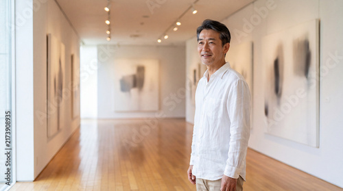 Obraz w ramie 開放的な美術館の展示室で絵画を鑑賞する50代男性 | 明るい空間