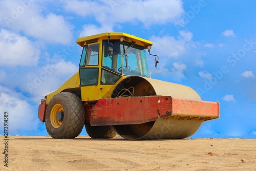 Konstfotografi road roller with yellow color, on construction site and sky background