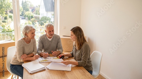 Senior Couple Reviewing Floor Plans with Advisor in New Home