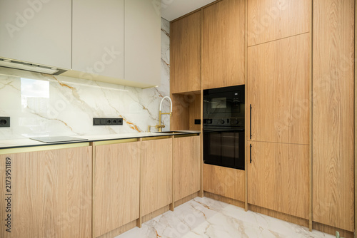 Фотография Oak veneer kitchen cabinetry with gold faucet and marble backsplash