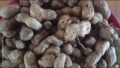 A close-up of boiled peanuts in a red plastic bowl on a wooden table; the theme is boiled food.