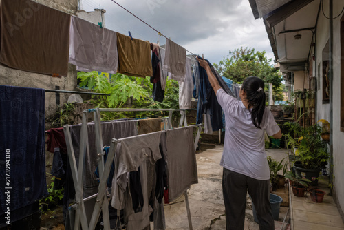 Person hanging laundry along an open air balcony in a modest tropical residence.generative AI