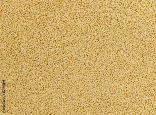 Dry yellow couscous grains forming a seamless texture