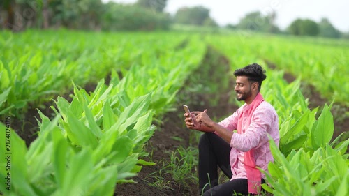 young indian farmer using smartphone at green turmeric agriculture field