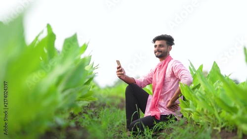 young indian farmer using smartphone at green turmeric agriculture field