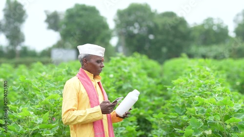 Senior Indian farmer using smartphone at cotton agriculture field 