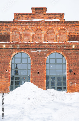 Snowy brick facade with arched entrance and festive lights