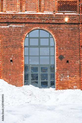 Snowy brick facade with arched entrance and festive lights