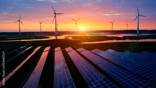 Fotografía Sunset over a large scale solar and wind energy farm with water reflections sola