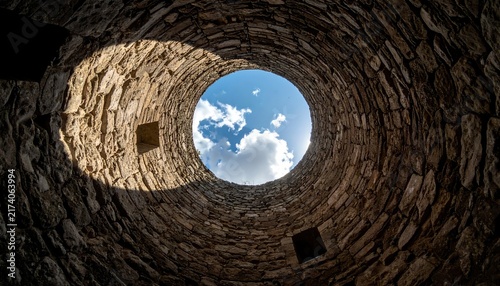 Obraz na płótnie Looking Through Rustic Stone Well the Bright Sky