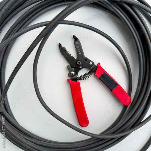 Bild auf Leinwand Red electrician pliers inside a circle of black power cable top view