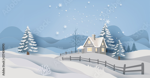 Paper cut style winter landscape with cozy cottage house, snow covered pine trees, falling snowflakes, and mountains background