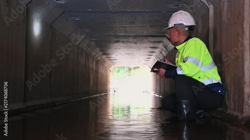 Industrial Worker Inspecting Concrete Drainage Tunnel for Maintenance and Safety