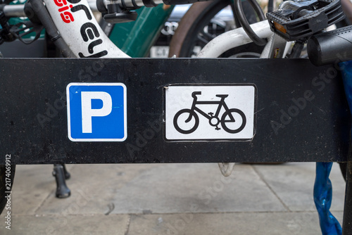 Fotografie Bicycle Parking Sign on Black Bike Rack with Park Symbol Outdoors
