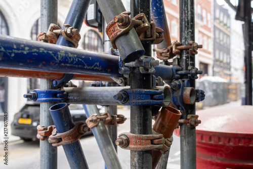 Obraz na płótnie Close-up of Rusty Scaffold Pipe Clamp on Urban Construction Site with City Backg