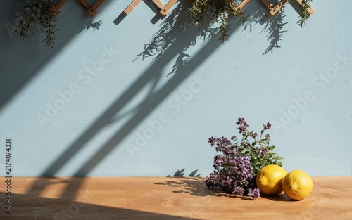 Two lemons and a bunch of purple flowers on a wooden table against a blue wall
