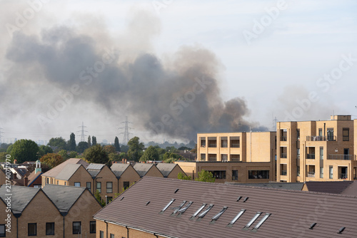 Canvas Print Thick Black Smoke Rising Over Residential Neighborhood With Modern Apartment Bui