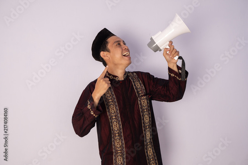 Expressive Portrait of a Young Man Enthusiastically Speaking into a Megaphone on a Simple Background