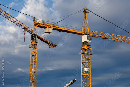 Konstfotografi Two yellow tower cranes against a dramatic cloudy sky in Austria